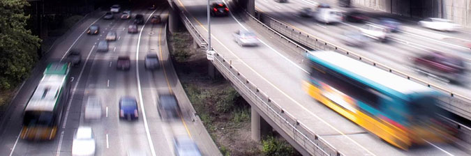 Traffic on the highway with buses, vans, cars and other vehicles moving in a blur.
