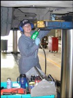 Photo of mechanic working on underside of bus